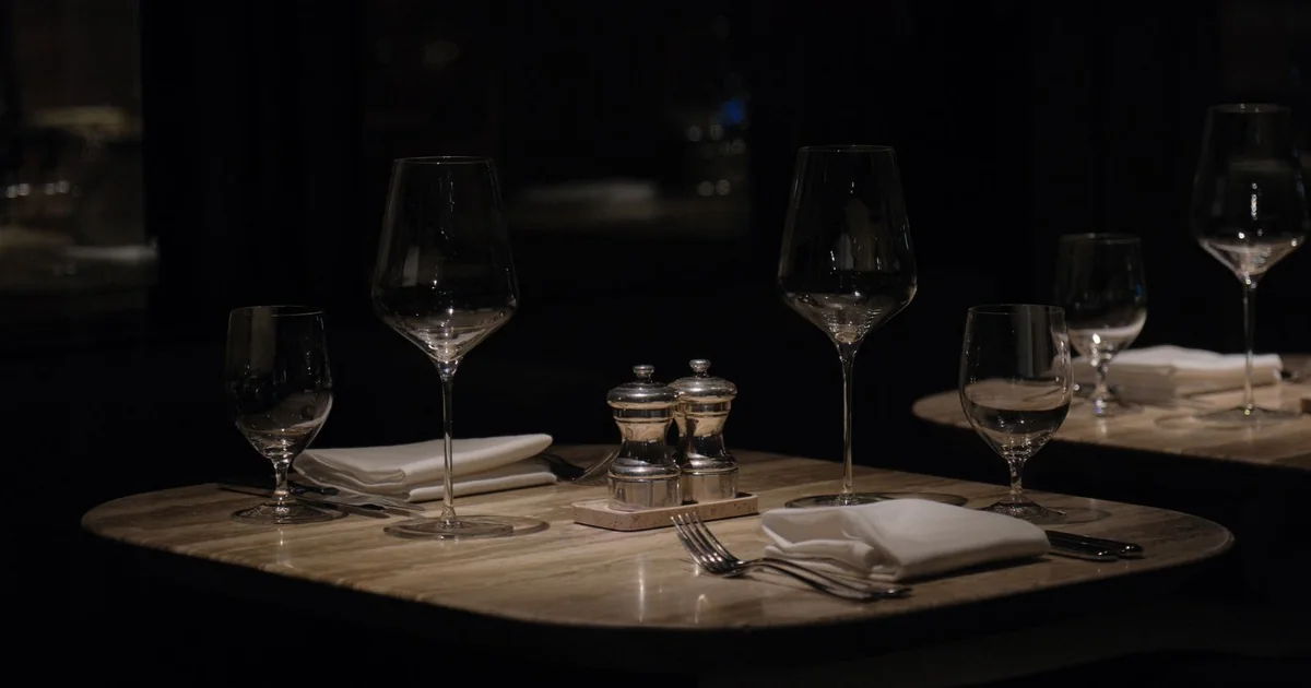 Table de restaurant dressée dans une salle sombre avec verres à vin